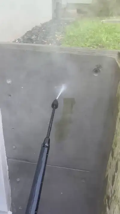 Lance haute pression projetant un jet sur une paroi en béton, traînée propre bien visible