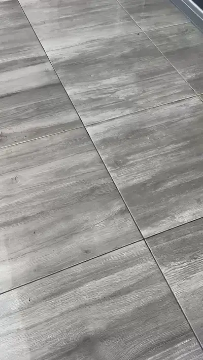 Grande terrasse en carrelage gris en cours de lavage, surface encore mouillée