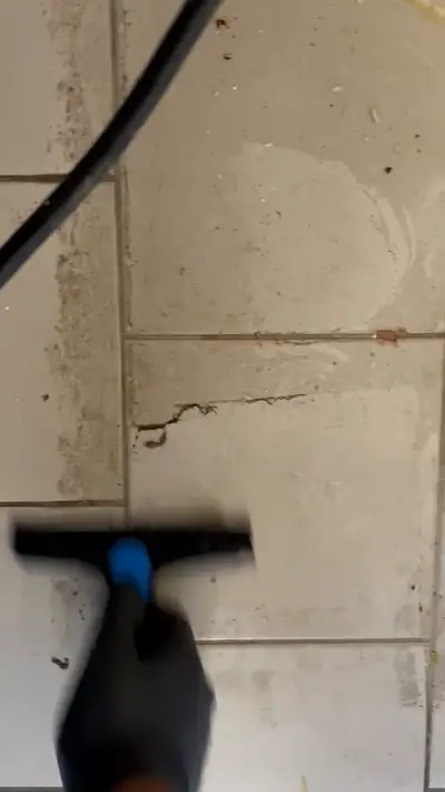 Buse de nettoyage sur un carrelage taché, la partie déjà traitée nettement plus claire