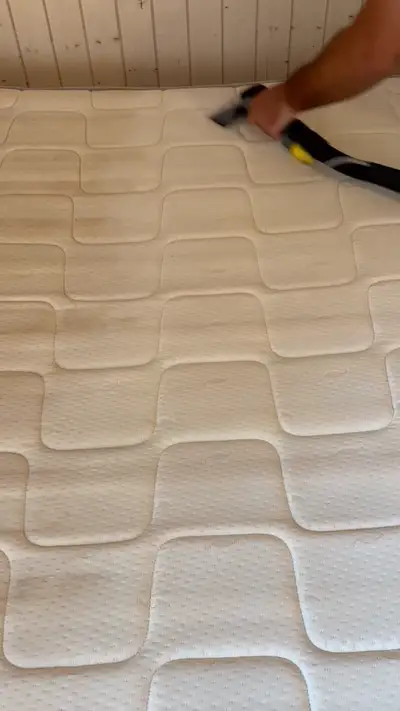 Main guidant un suceur de nettoyage sur un matelas clair